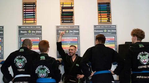 Trainerteam in Educate-Sports-Jacken vor den Skill-Tafeln der Jiu-Jitsu-Kurse