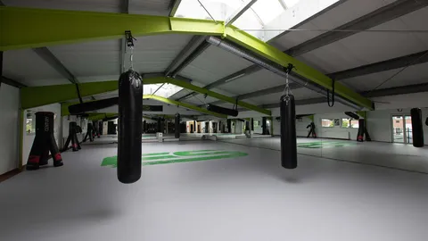 Trainingshalle von Educate Sports mit Boxsäcken und Mattenfläche